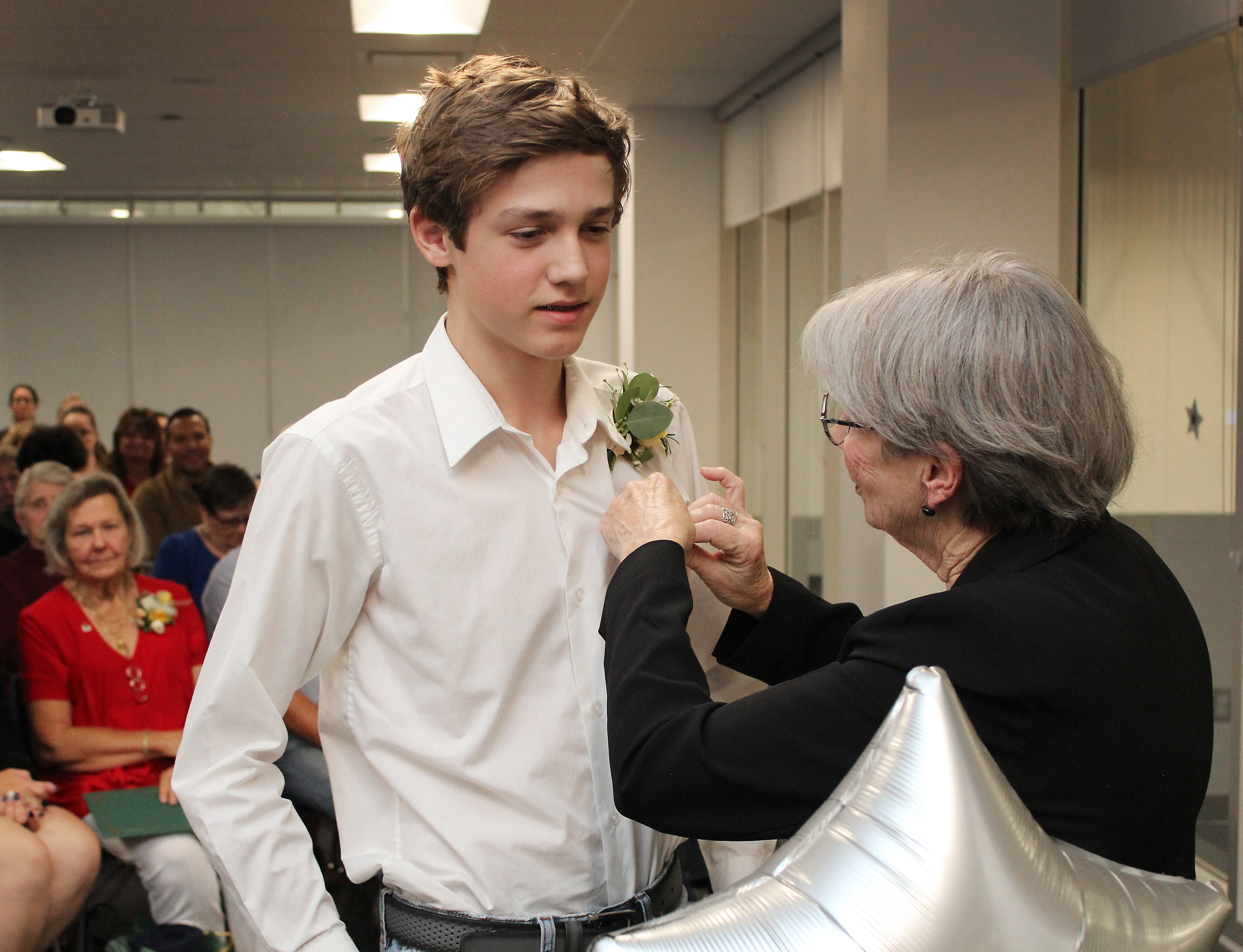 Mayor Cheryl Ganann places a Township pin on Carson McFarlane